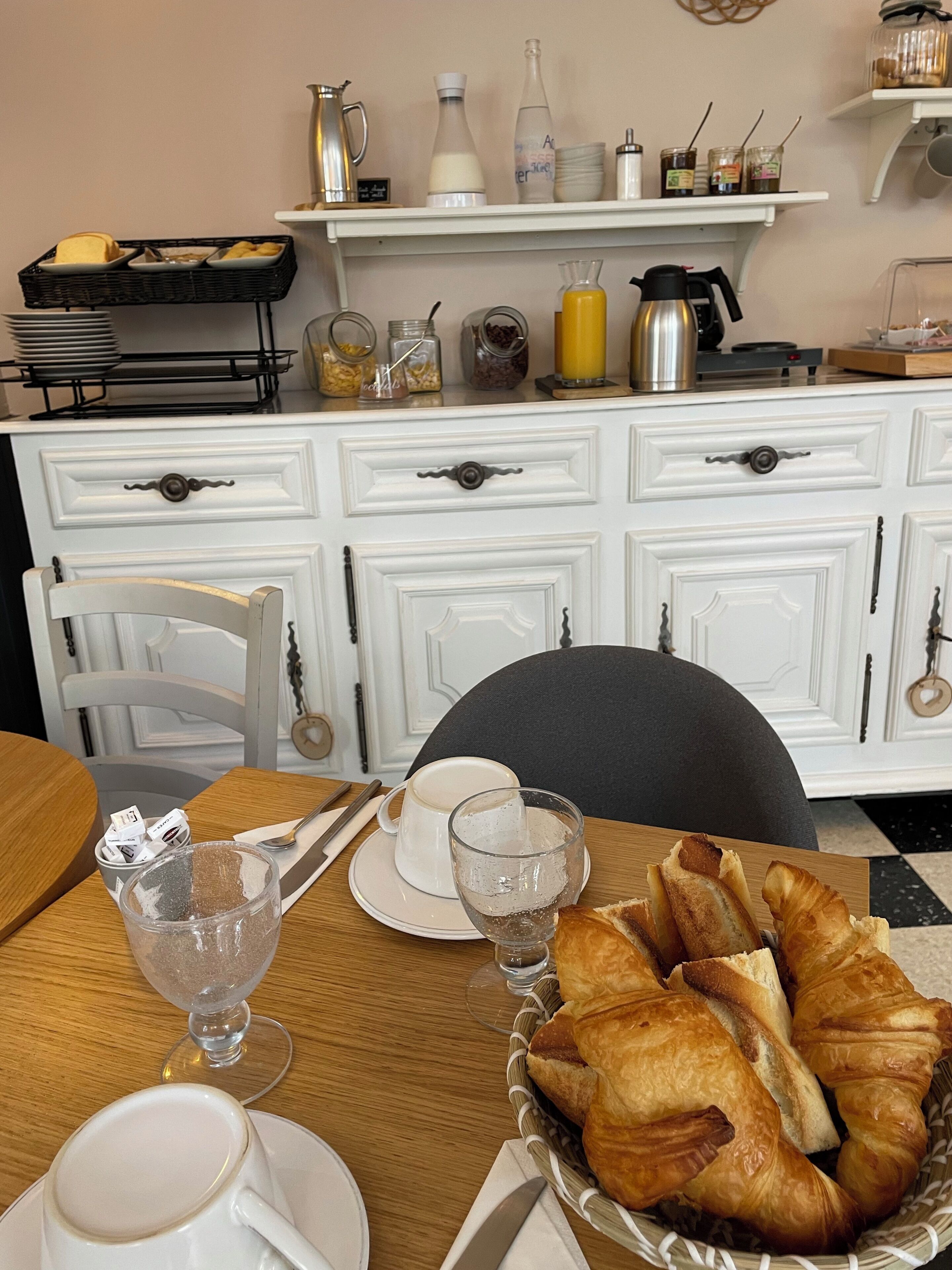 A breakfast setting with croissants, coffee, and juice on a table.