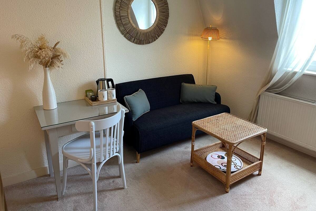 Une pièce chaleureuse avec un canapé bleu foncé, une chaise blanche, une petite table et une lampe.