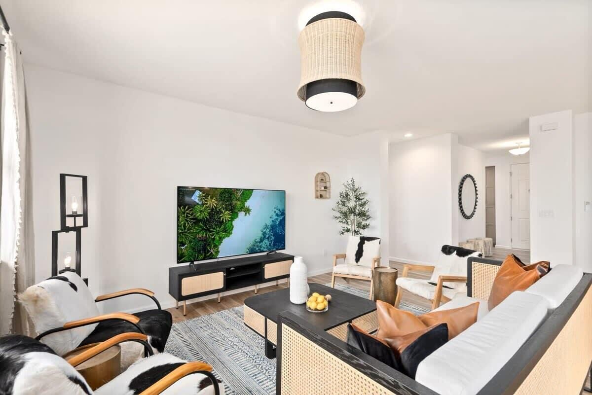 A modern living room with a flat-screen TV, comfortable seating, and a decorative plant.