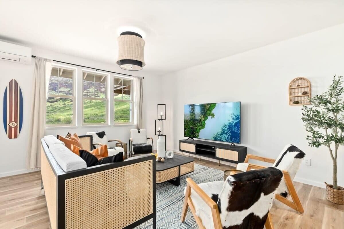 Een moderne woonkamer met een grote televisie, een bank, een eettafel en een potplant.