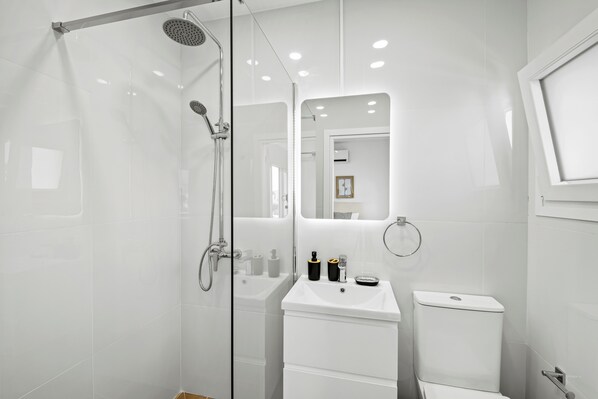 Une salle de bain moderne avec une douche à parois de verre, un lavabo blanc et des toilettes.