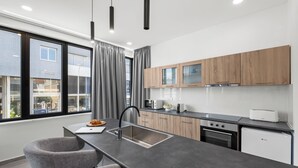 Una cocina moderna con una isla central, pileta de acero inoxidable, muebles de madera y vista al exterior.