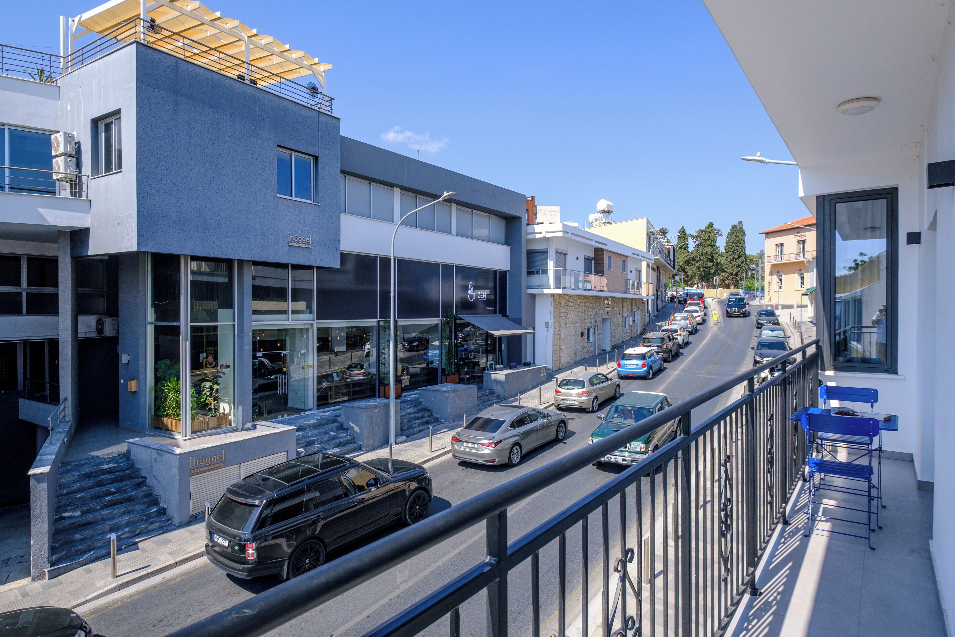 Un edifici modern amb façana de vidre, entrada visible i un carrer amb cotxes estacionats.