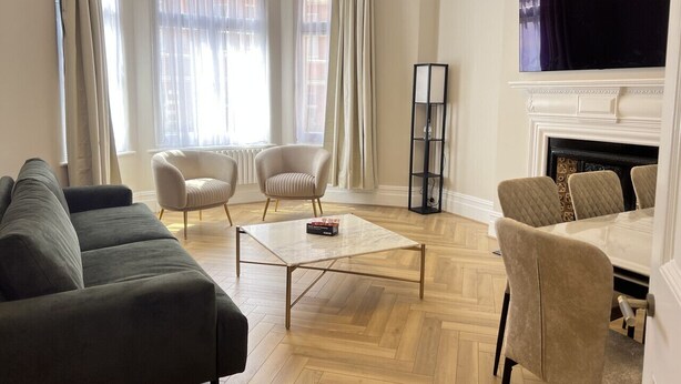 Uma sala de estar moderna com um sofá, poltronas, uma mesa de centro e uma lareira.