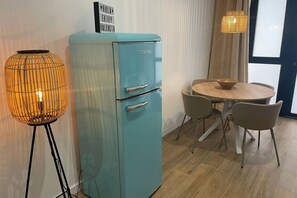 A teal vintage refrigerator, a round wooden table with four chairs, and a tall floor lamp with a woven shade. - Travel Habitat Mediterranean Suite 7 (València)