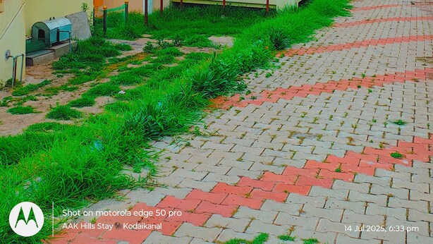 A residential area with houses featuring red roofs and yellow walls, a paved walkway, and a staircase leading to a balcony. - AAK Hills Stay, Individual Villa, Kodaikanal (Vilpatti)