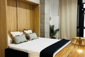 A modern bedroom with a large bed, wooden wardrobe, and a unique lamp.
