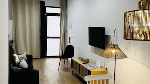 Una sala moderna con un sofá, una silla, una mesita, un televisor y una lámpara.