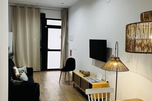 A modern living room with a sofa, a chair, a small table, a TV, and a lamp.