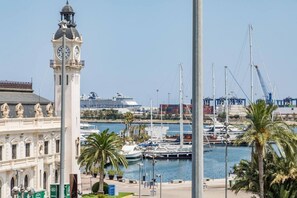 A coastal marina with a prominent clock tower, yachts, and a cruise ship in the background. - Travel Habitat Mediterranean Suites 8 (València)