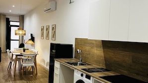 Cocina compacta con lavadora, lavaplatos y comedor con mesa y sillas.