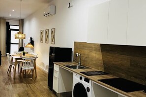 A compact kitchen with a washing machine, a sink, and a dining area with a table and chairs.