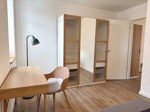 Une pièce comprenant un bureau en bois, une chaise, un lampadaire et une armoire aux portes en verre.