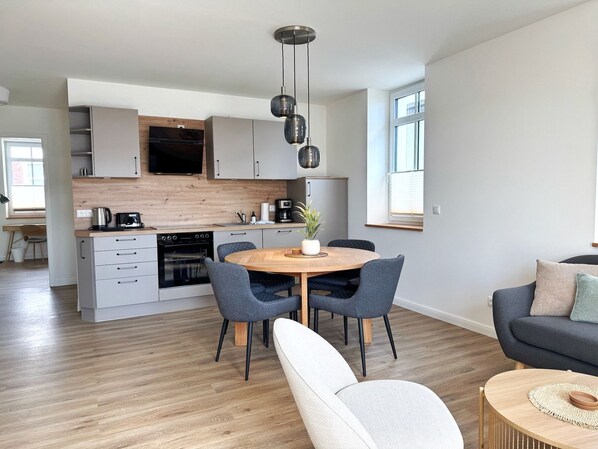 A modern kitchen with a central island, built-in appliances, and pendant lighting. - Harbor master Ole - Maritime coziness in a modern new building (Sassnitz)