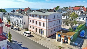 Ein mehrstöckiges Gebäude mit flachem Dach in einer Küstenstadt mit freiem Blick auf das Meer.