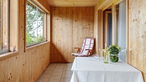 A wooden-paneled room with a table, a chair, and a vase of flowers. - Room 'Zirbengeist' with Mountain View, Shared Garden and Wi-Fi (Sibratsgfäll)