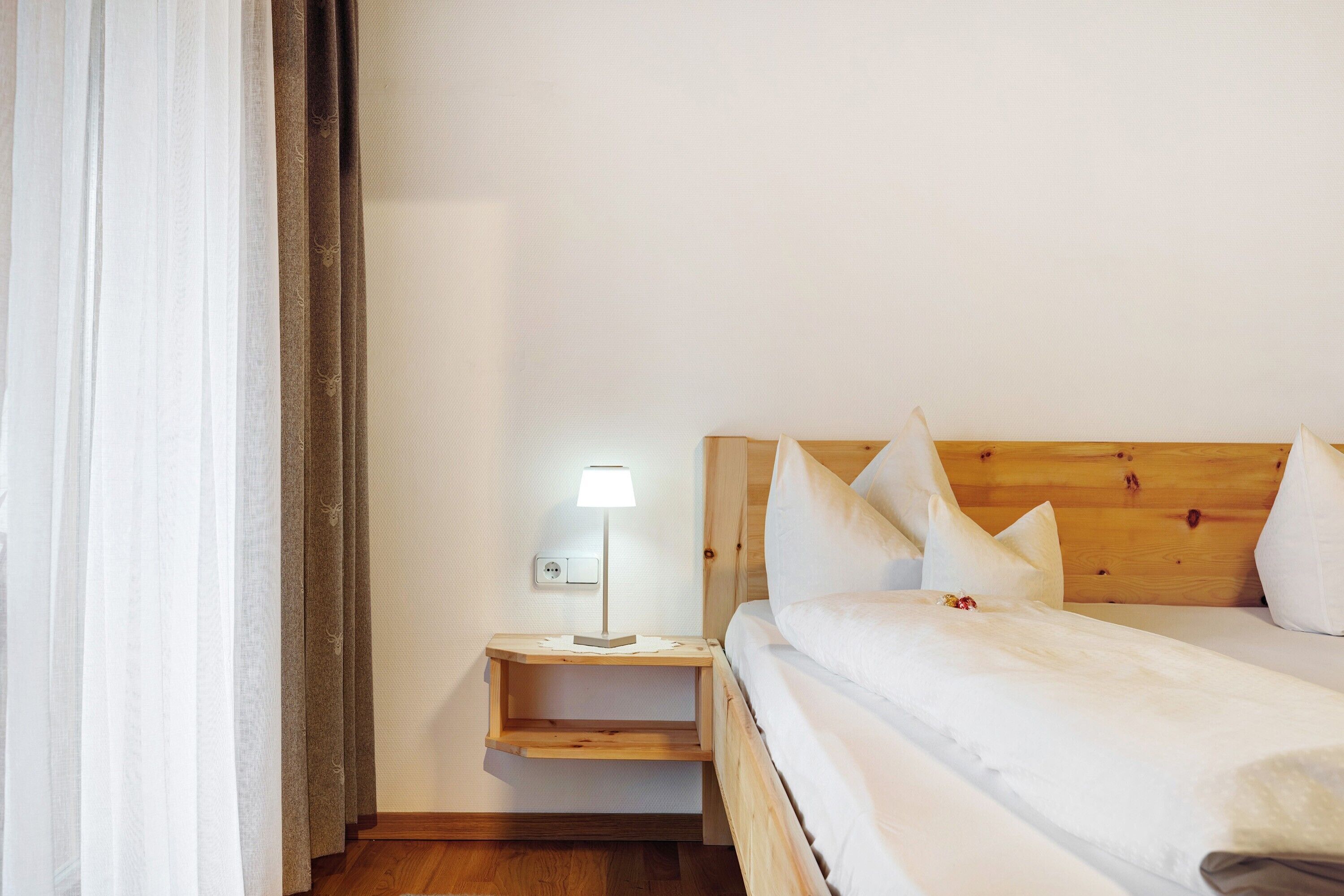 Ein Schlafzimmer mit einem Holzkopfende, einem Nachttisch mit Lampe und einem Bett mit weißer Bettwäsche.