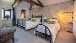 A bedroom with two beds, a window with curtains, a stone wall, and a hanging lamp. - Mas Combefa, a haven of serenity between history and nature. (Combefa)
