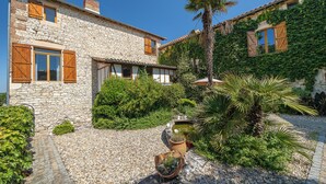 A stone house with wooden shutters, a gravel driveway, and a small pond. - Mas Combefa, a haven of serenity between history and nature. (Combefa)