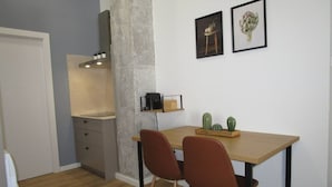 Una cocina compacta con una mesa de madera, dos sillas, una cafetera y un cactus en la mesa.