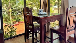 A room with a large window, a wooden table with chairs, and a teapot on the table. - Laa House Hoi An (Da Nang)