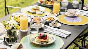 A table set for breakfast with various dishes, drinks, and a vase of flowers.