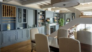 A dining area with a wooden table and chairs, grey cabinetry with wine racks, and a staircase leading to an upper level.