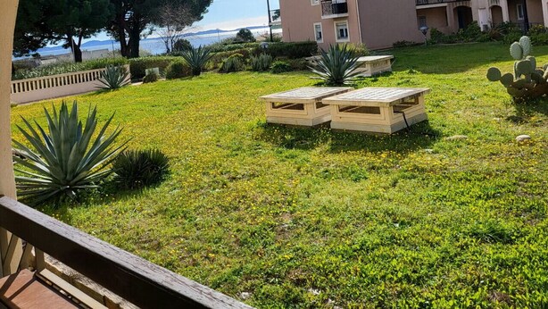 Visão através de um arco de um edifício com um jardim em frente, com mesa de bilhar e cactos.