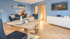 Un salon moderne comprenant une table à manger, un canapé, un téléviseur et un coin cuisine.