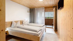 Habitació de fusta amb dos llits, una televisió i una finestra amb cortines.