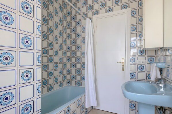 A bathroom with patterned tiles, a bathtub, a white door, and a sink. - Villa 'Guadiaro' with Mountain View, Wi-Fi and Air Conditioning (Marbella)