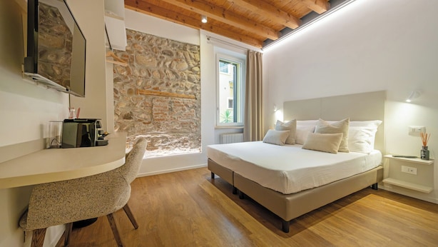 A bedroom with a stone wall, a bed, a desk, and a chair. - ApartmentsArena - Mustacchi Rooms (Verona)
