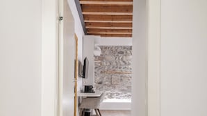 A hallway with a wooden floor, a patterned rug, and a stone wall in the background. - ApartmentsArena - Mustacchi Rooms (Verona)