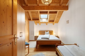 Un dormitorio con techo de madera, tragaluz, cama, mesita de noche y armario.