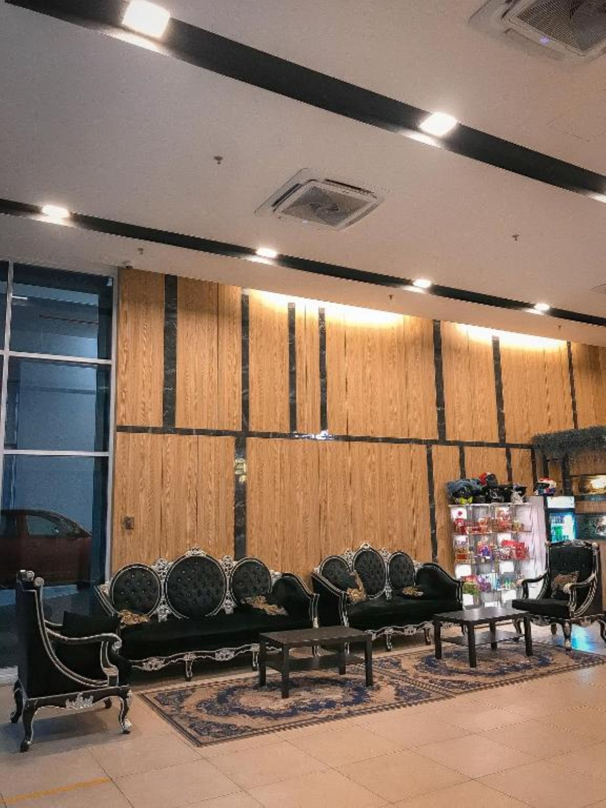 A reception area with a wooden wall, black upholstered chairs, a small table, and a shoe display.