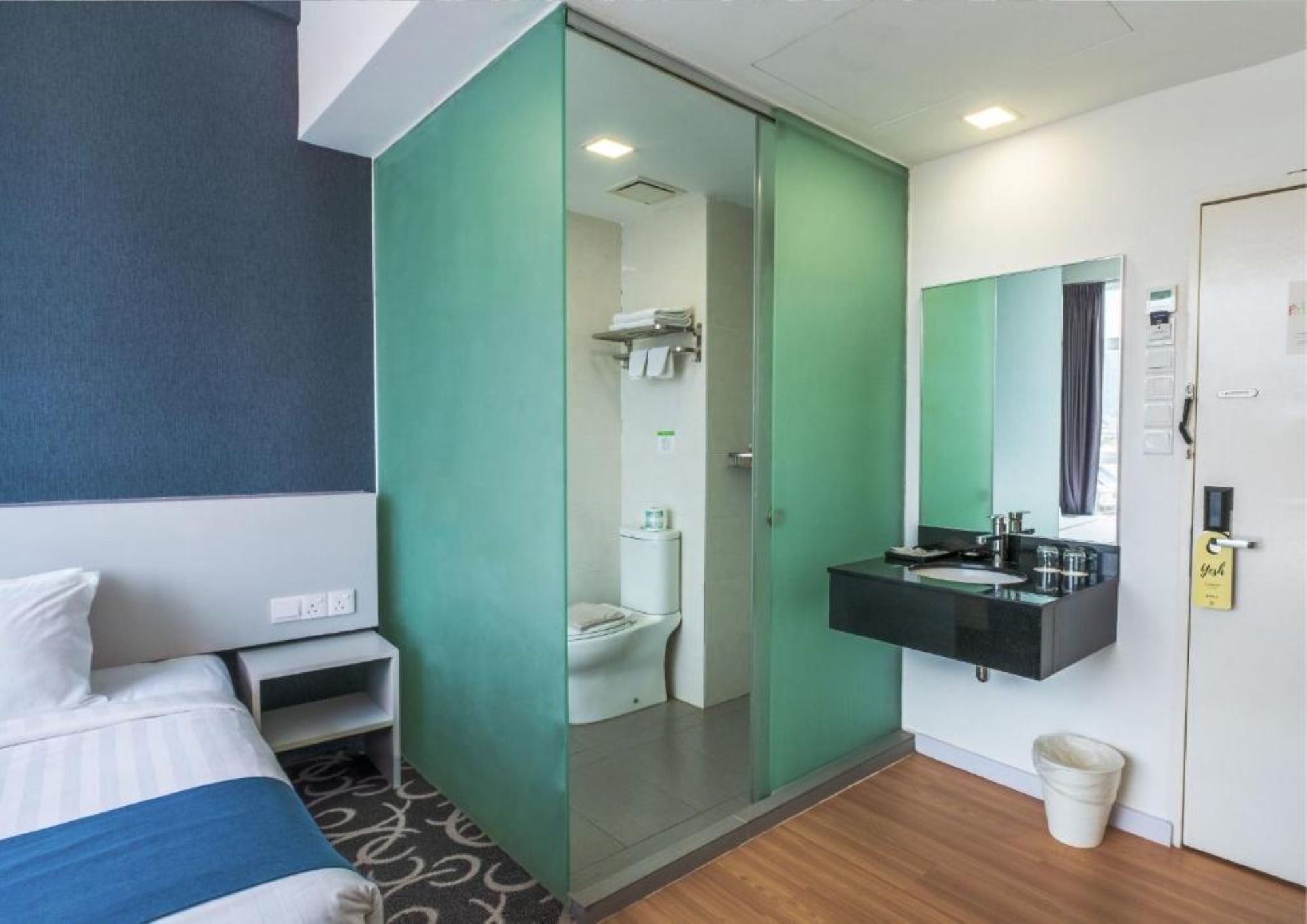 Ein Hotelzimmer mit Bett, Badezimmer mit Toilette und Waschbecken sowie einem Spiegel über dem Waschbecken.