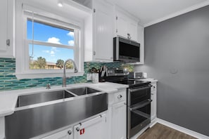 A modern kitchen with a stainless steel sink, a built-in oven, and a microwave. - Gulf Village 2 Bedroom Cottage - 2 Pools - Fall Family Fun! (Gulf Shores)
