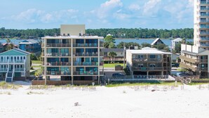 Un hotel frente al mar con varios pisos, balcones y una zona de piscina.