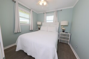 Une chambre à coucher avec un grand lit, deux tables de chevet avec des lampes et un ventilateur de plafond.