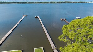 Una propiedad frente al lago con dos muelles que se adentran en sus tranquilas aguas, rodeada de vegetación.
