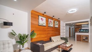 A modern living room with a sofa, coffee table, and a wooden accent wall with framed artwork.