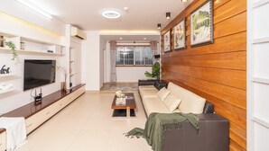 A modern living room with a sofa, coffee table, TV, and wooden paneling.