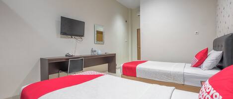A hotel room with two beds, a desk with a TV, a mirror, and a door.