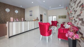 A reception area with a reception desk, red chairs, and a decorative wall with clocks. - Hotel O Makassar near Pantai Losari formerly Hotel Astra Novilia (Makassar)