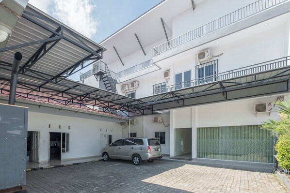 A multi-story building with a covered parking area, a staircase, and a car parked in the driveway. - Hotel O Makassar near Pantai Losari formerly Hotel Astra Novilia (Makassar)