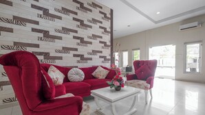 A living room with a red sofa, a white coffee table, and a patterned wall. - Hotel O Makassar near Pantai Losari formerly Hotel Astra Novilia (Makassar)