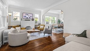 A spacious living room with a fireplace, wooden flooring, and a dining area with a table and chairs. - 5280 Oasis - Hot Tub + Walk to Sloan's Lake (Denver)