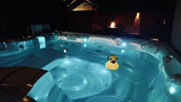 A hot tub with multiple jets, a duck float, and a wooden deck area with chairs. - 5280 Oasis - Hot Tub + Walk to Sloan's Lake (Denver)