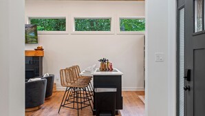 A modern kitchen with a dining area, wooden flooring, and three windows with a view of greenery. - Under 1 mile to Dollywd, 5 mins Pkwy - 2 Kings/2 BA - Small fam or couples (Pigeon Forge)