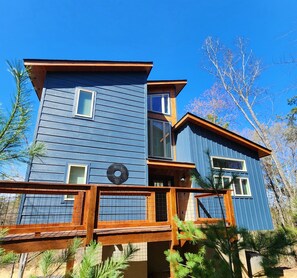 A two-story building with a blue exterior, a wooden deck, and a circular sign with text. - Under 1 mile to Dollywd, 5 mins Pkwy - 2 Kings/2 BA - Small fam or couples (Pigeon Forge)
